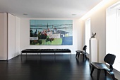 Black bench in front of large picture on wall