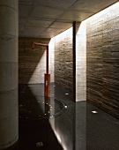 Free-standing, open shower in bathroom with concrete walls & pillars