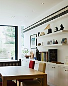 Dining table and chairs in front of white sideboard and shelves