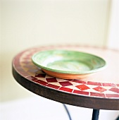 Green plate on round mosaic table