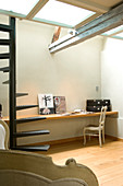 Schlichtes Zimmer mit Wendeltreppe vor Ablage an Wand und Rokokostühlchen