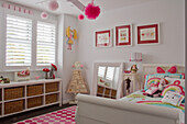 Girls' room in white and pink with bed and toy storage