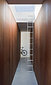 Hallway with wooden cupboards, ladder and bicycle