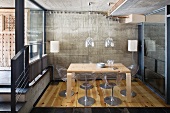 Dining area in concrete and glass structure with wooden table and designer chairs