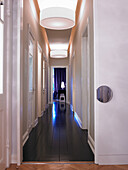 Long hallway with dark wooden floor and white ceiling lights