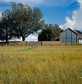 View of house with glass wall from field