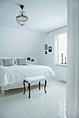 Monochromes Schlafzimmer mit weißer Bettwäsche und Kristalllüster