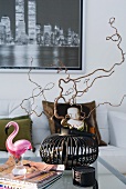 Hazelnut sprigs in an iron basket and a glass flamingo on a coffee table in a modern living room