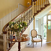 Entrance area with wooden staircase, floral decorations and classic chair