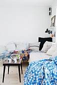 Comfortable, vintage-style corner sofa with scatter cushions and blankets and goldfish bowl on side table