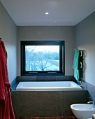 Grey-tiled bathtub in front of window