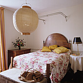 Schlafzimmer mit Holzbett, floraler Bettwäsche und Hängeleuchte