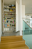 Open larder unit and wooden staircase with glass railing