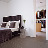 Bedroom with dark upholstered bed and adjoining walk-in wardrobe