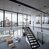 Modern living room with gallery, large windows and design-orientated furnishings