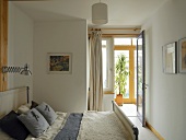 Small, simple bedroom - double bed with rustic fabrics beneath retro lamp with telescopic arm