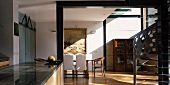 Metallwendeltreppe in lichtdurchflutetem Wohnraum mit antiken Einzelstücken im Essbereich und modernem Küchenblock