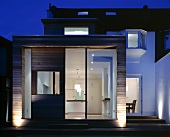 Wood-clad, cubic extension on traditional house at twilight