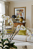 Living room with white orchids, white sofa and golden Buddha decoration