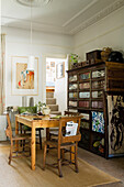 Wooden table with chairs in front of antique cupboard in dining room with staircase