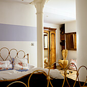 Bedroom with brass bed, pillars and wooden wardrobe