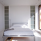 Minimalist bedroom with white bed and built-in shelves