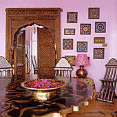 Oriental-inspired dining area with carved wooden door, pink wall and decorations