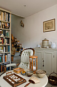 Reading corner with antique armchair, hourglass and wall shelf full of books