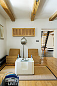 Two rattan armchairs and modern side table in minimalist living room with exposed ceiling beams