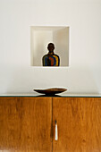 Wooden chest of drawers with bowl, figurine in wall niche