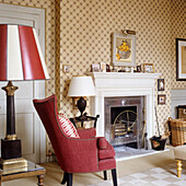 Armchair and fireplace in traditional living room with patterned wallpaper