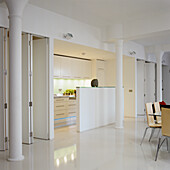 Kitchen with white cupboards and dining table in the open-plan living area