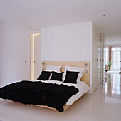 Bedroom with minimalist design, white bed linen, black pillows and black fur