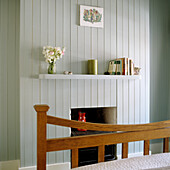 Fireplace with white wood panelling and shelf with decorations and books