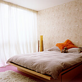 Bedroom with wooden bed, fluffy carpet and patterned wallpaper