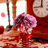 Purple flowers in red glass with pattern