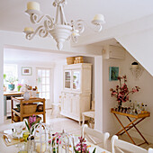 Open-plan kitchen with dining area, white furniture and chandelier