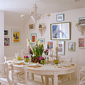 Set dining table with candlesticks and flower arrangements, surrounded by colourful pictures on the wall