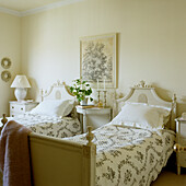 Beds with floral covers and antique bedside tables in the bedroom