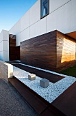 Modern house facade with white cladding and wooden planes in warm shades of brown