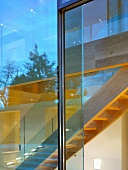 Blick durch Glasfront auf Treppe aus Holz