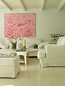 Helles Wohnzimmer mit großem Rosenbild, weißen Möbeln und Katze