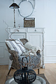 Woven armchair with cushions, blanket and decorative wreath in a white room