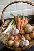 Basket of fresh vegetables: carrots, leeks, garlic and onions