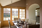 Frühstückstisch mit gradlinigen Korbstühlen in Anbau mit umlaufender Fensterfront