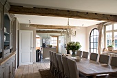 Lange Tafel und Hussen-Stühle im Landhaus-Esszimmer mit anschliessender offener Küche