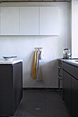 Kitchen with white wall and white wall units, black floor and black cupboards