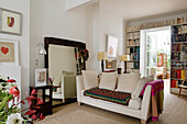 Living room with couch, bookshelf and view of the conservatory