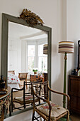 Mirror and wooden chair in a classic living room with natural light