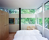Bedroom in house made of glass and wood elements in forest